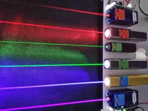 Six commercial lasers in operation, showing the range of different colored light beams that can be produced, from red to violet. From the top, the wavelengths of light are: 660nm, 635nm, 532nm, 520nm, 445nm, and 405nm.
