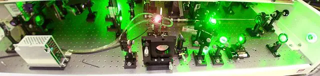 View on the Coherent ODIN titan-sapphire ultrashort pulse amplifier in the Physical institute, CAS, Prague. The intense green pump beam (faintly visible in the air) comes from left, supplied by Nd:YAG laser (Pavg = 10 W) and passes twice through the Ti:sapphire crystal, which is placed in a Peltier- and water-cooled holder. The seed pulse is created in a mode-locked laser Mira, becomes chirped through pulse stretcher (optics hidden behind the amplifier) and pases 8 times the cycle consisting of the Ti:sapphire crystal, two little mirrors on the left and right, a big mirror in front of the crystal and 8-holes spatial filter right of the mirror. The averaged output power is 1 W in approx. 70 fs pulses @ 1 kHz. The wavelenght of Ti:sapphire laser covers a broad range near 800 nm.